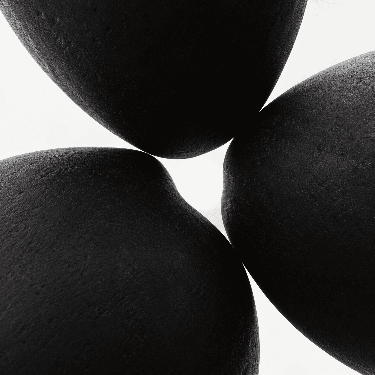 Three matte black sculptural forms surrounding a bright circular opening